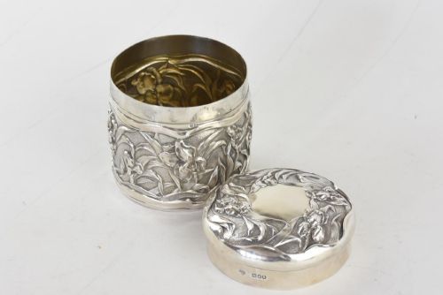fig 2. A cylindrical Art Nouveau sterling silver box with a fitted lid, decorated with raised repousse iris motifs.