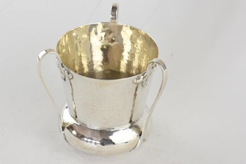 fig 1. A hand-hammered silver three-handled tyg cup with a planished finish and stylized handle mounts.