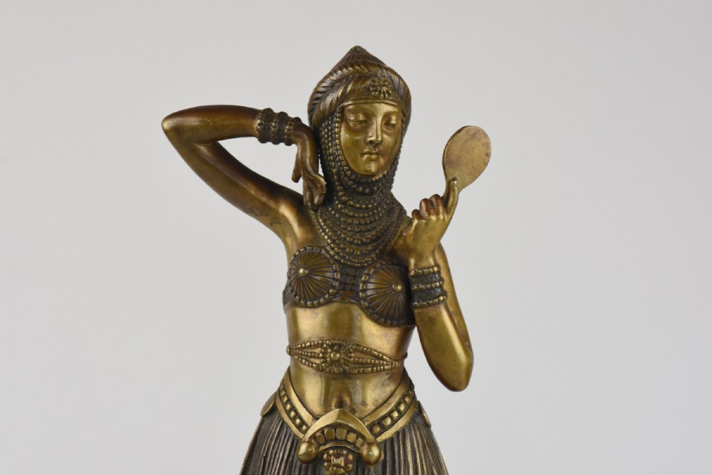 An Art Deco bronze figure depicting a female dancer in theatrical attire holding a small hand mirror, mounted on a square onyx plinth. View III