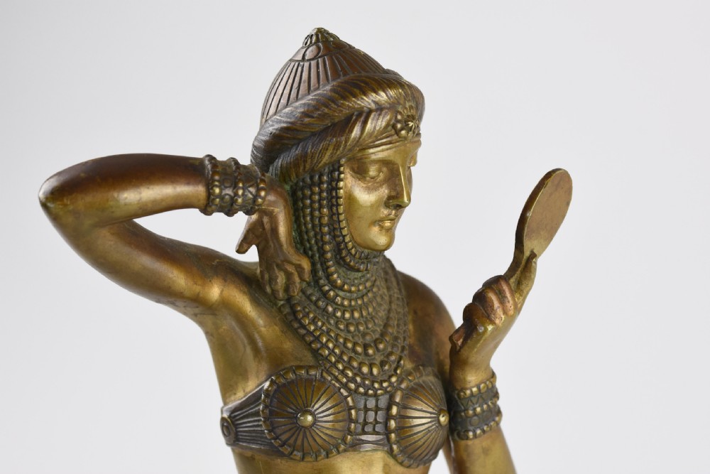 An Art Deco bronze figure depicting a female dancer in theatrical attire holding a small hand mirror, mounted on a square onyx plinth. View II