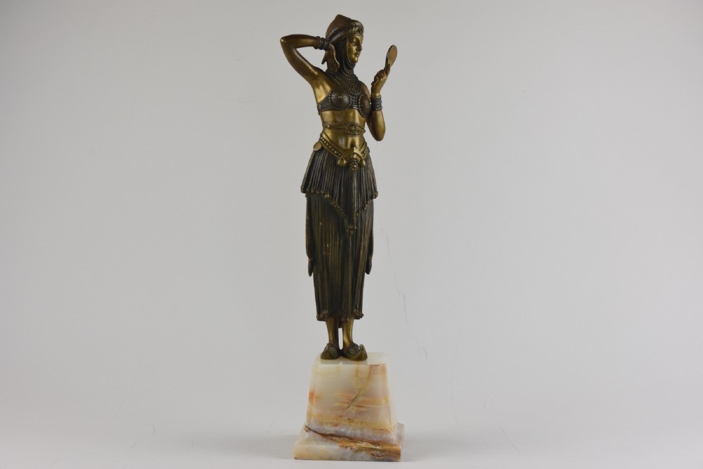 An Art Deco bronze figure depicting a female dancer in theatrical attire holding a small hand mirror, mounted on a square onyx plinth.
