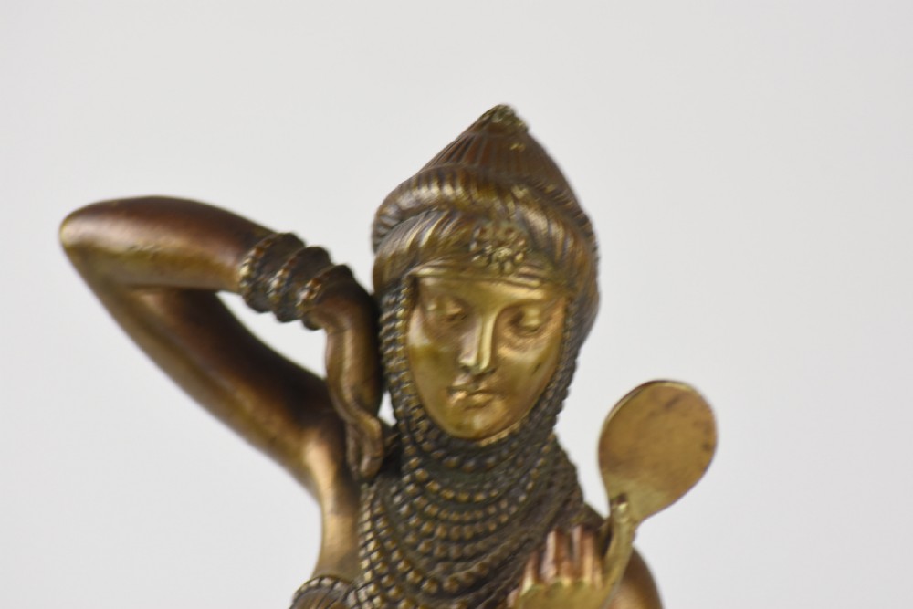 An Art Deco bronze figure depicting a female dancer in theatrical attire holding a small hand mirror, mounted on a square onyx plinth. View IX