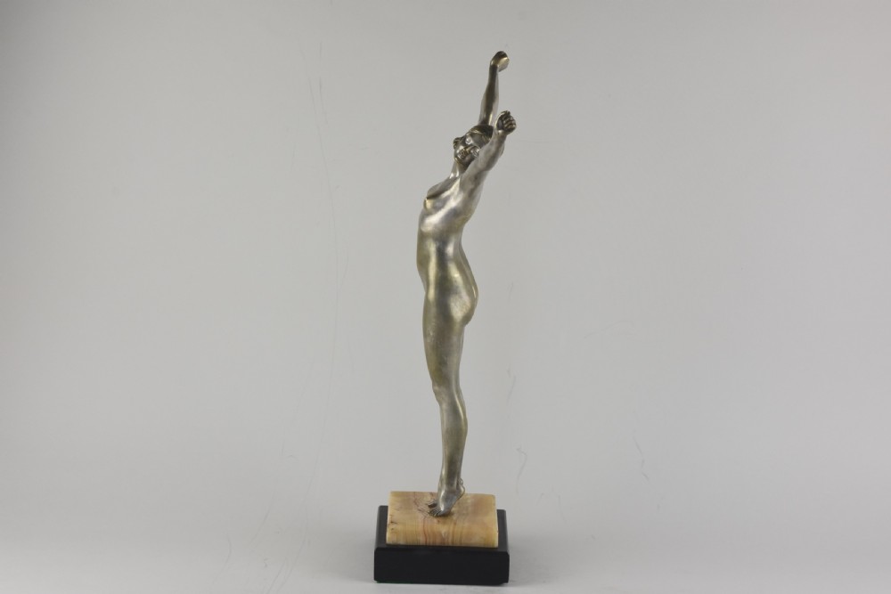 An Art Deco silvered bronze sculpture depicting a nude female figure with raised arms standing atop a tiered marble and black base. View III