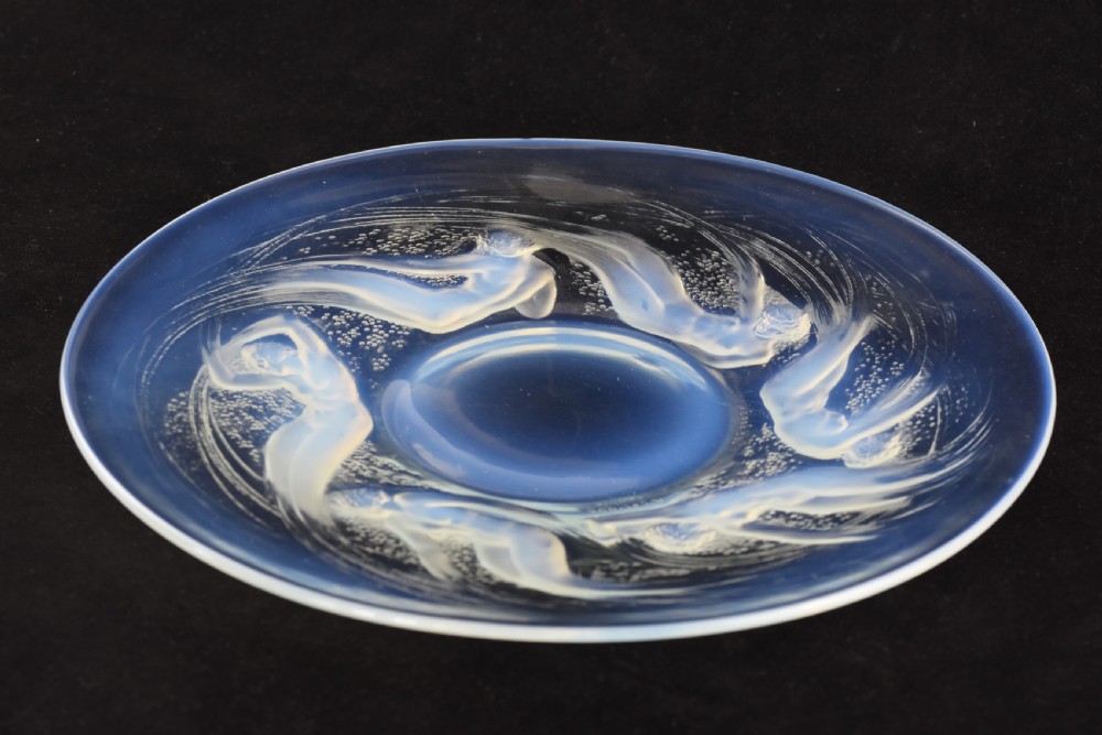 A circular opalescent glass plate featuring press-moulded relief figures of swimming nymphs amidst swirling water motifs.