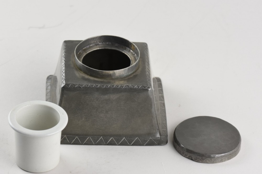 A square tapered hand-hammered pewter inkwell featuring a circular lid and stamped chevron borders around the edges. View III