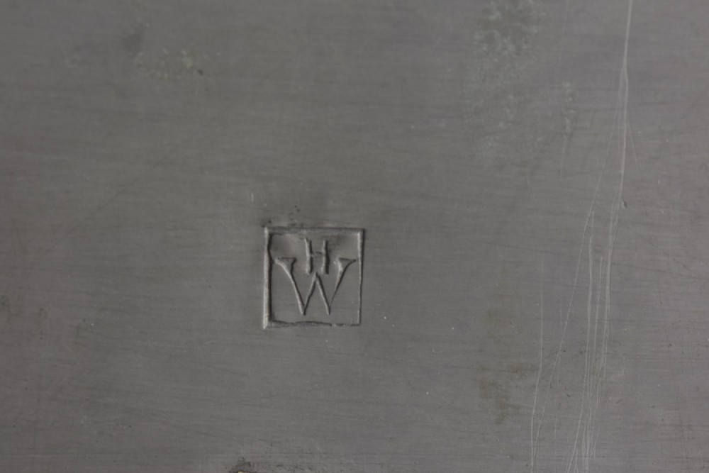 A square tapered hand-hammered pewter inkwell featuring a circular lid and stamped chevron borders around the edges. View V