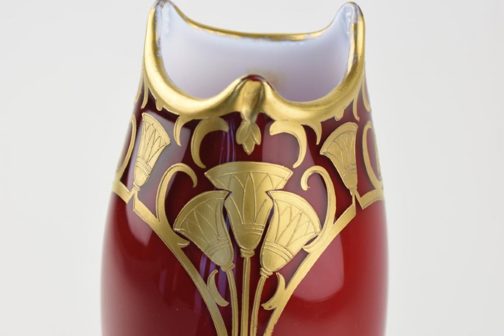 An Art Nouveau deep red glass vase with gilded enamel lotus motifs, featuring a shaped rim and a four-footed base. View II