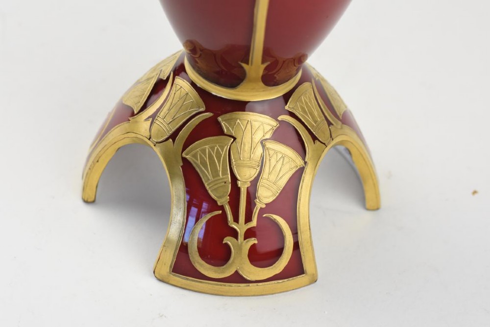 An Art Nouveau deep red glass vase with gilded enamel lotus motifs, featuring a shaped rim and a four-footed base. View III