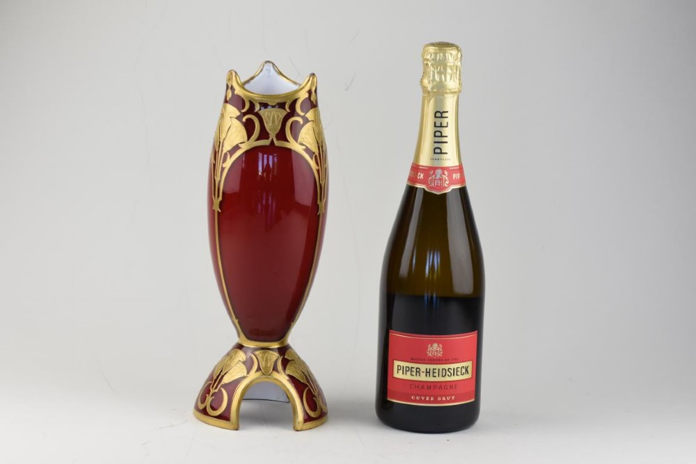 An Art Nouveau deep red glass vase with gilded enamel lotus motifs, featuring a shaped rim and a four-footed base. View V