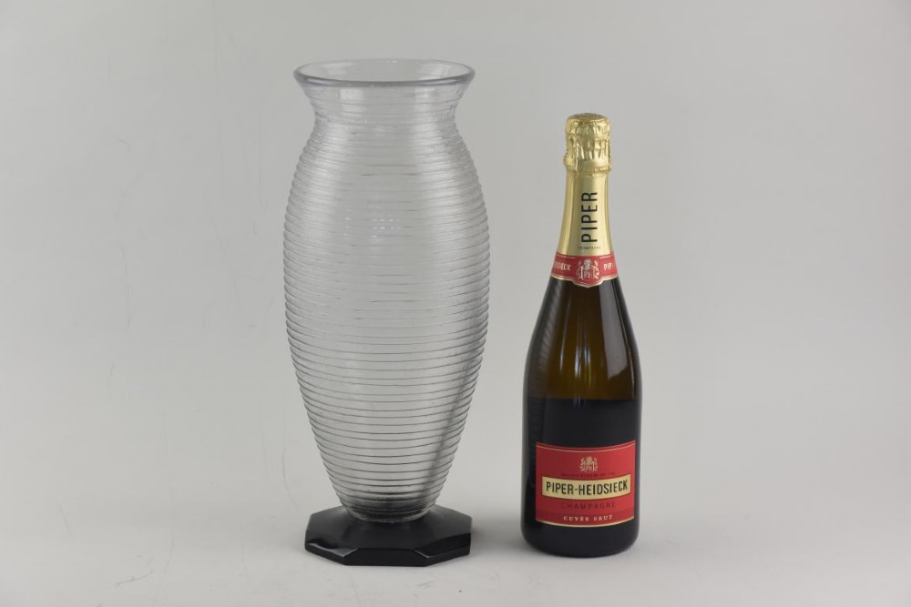 A ribbed grey glass vase with a flared rim resting on an octagonal black base. View VI