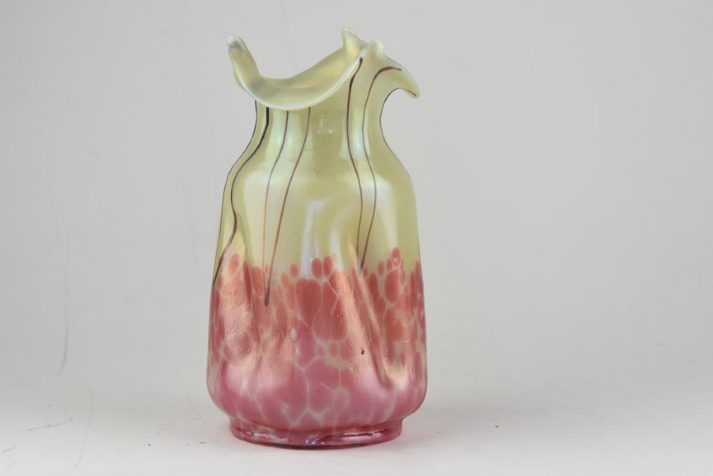An Art Nouveau iridescent glass vase featuring a pale yellow upper section with dark glass trailing and a speckled pink lower base with a ruffled rim. View II