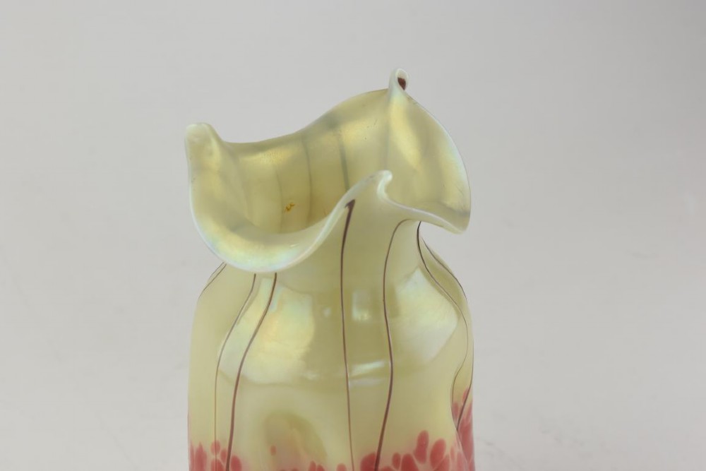 An Art Nouveau iridescent glass vase featuring a pale yellow upper section with dark glass trailing and a speckled pink lower base with a ruffled rim. View V