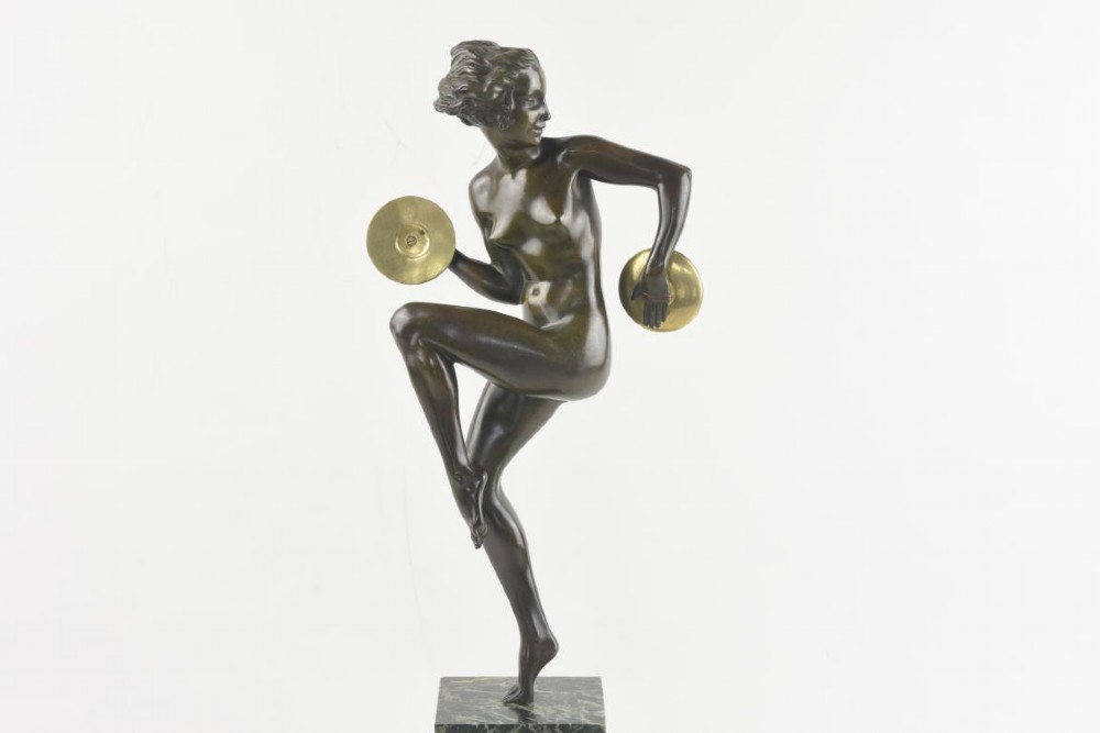 An Art Deco dark patinated bronze figure of a female dancer holding cymbals, balanced on one leg atop a tall green-veined marble base. View II