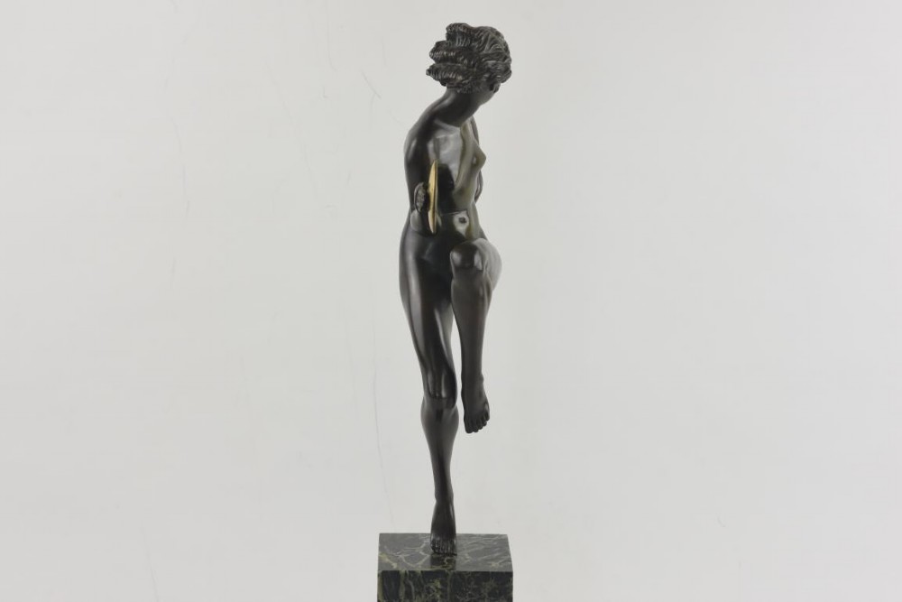 An Art Deco dark patinated bronze figure of a female dancer holding cymbals, balanced on one leg atop a tall green-veined marble base. View III