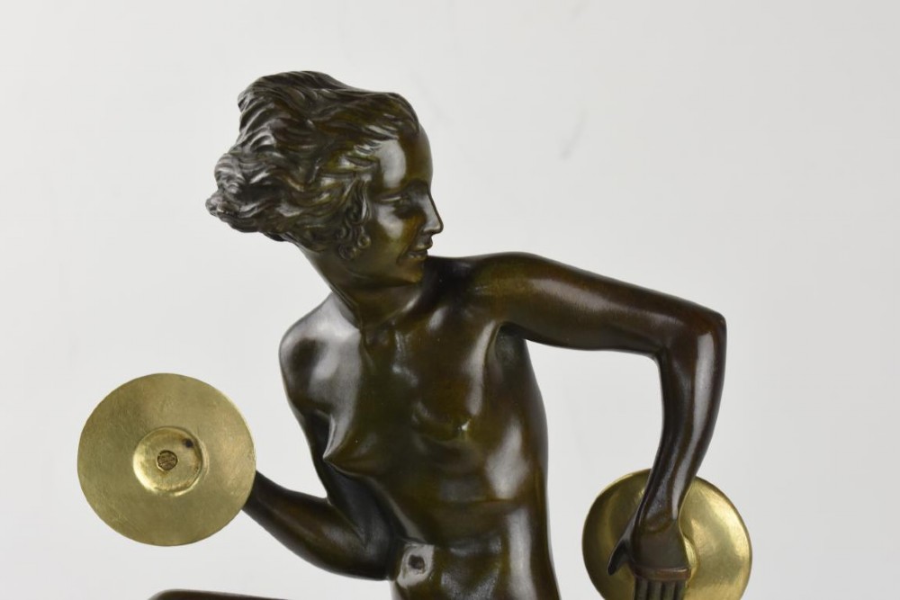An Art Deco dark patinated bronze figure of a female dancer holding cymbals, balanced on one leg atop a tall green-veined marble base. View VI