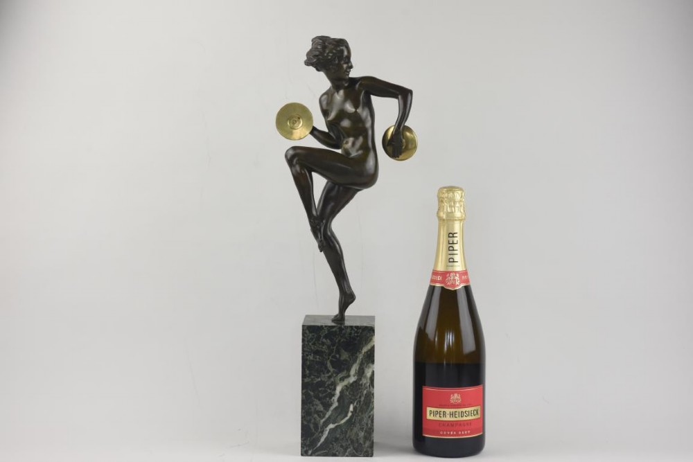 An Art Deco dark patinated bronze figure of a female dancer holding cymbals, balanced on one leg atop a tall green-veined marble base. View IX