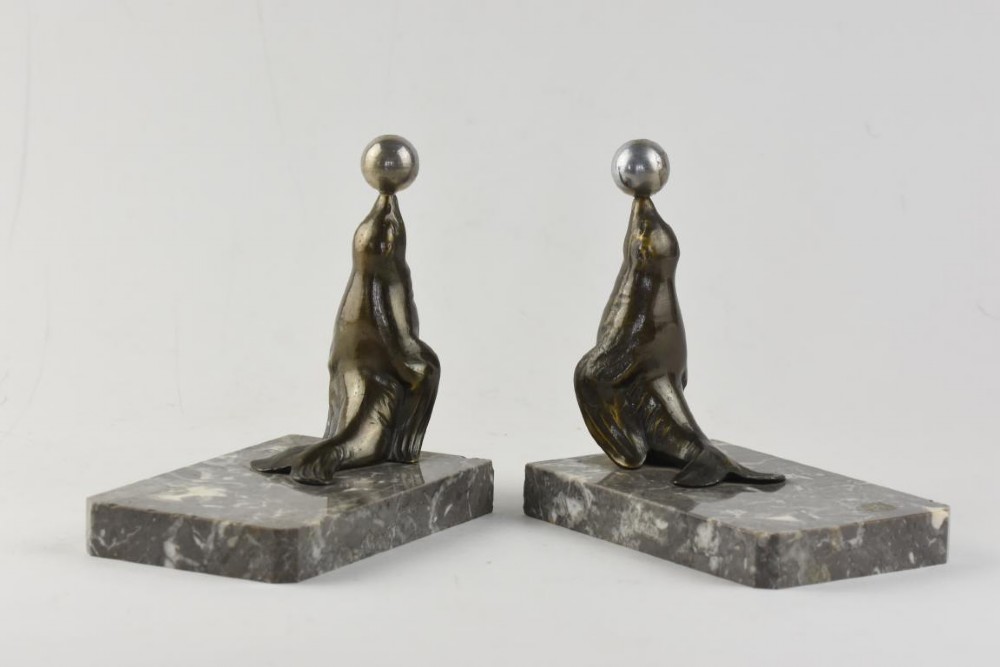 A pair of Art Deco metal sea lions balancing chrome spheres on their noses, mounted on rectangular grey marble bases. View III