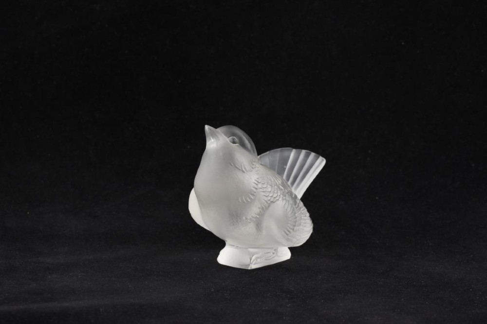 A frosted crystal glass figurine of a small sparrow perched on an integrated base with its head tilted upwards.