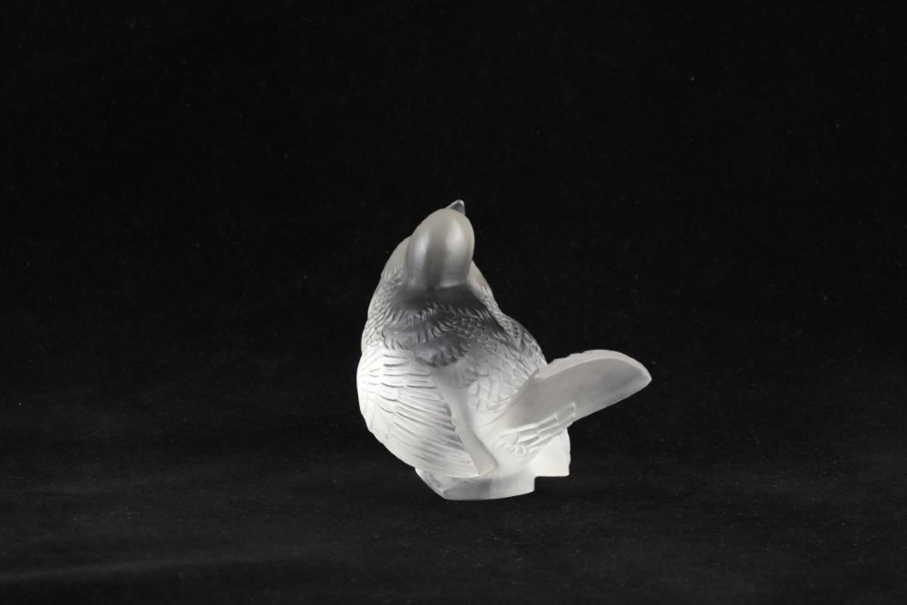 A frosted crystal glass figurine of a small sparrow perched on an integrated base with its head tilted upwards. View II
