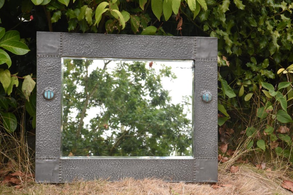A rectangular Arts and Crafts wall mirror featuring a hammered pewter metal frame decorated with corner rivets and two circular turquoise ceramic cabochons on the side borders. View II