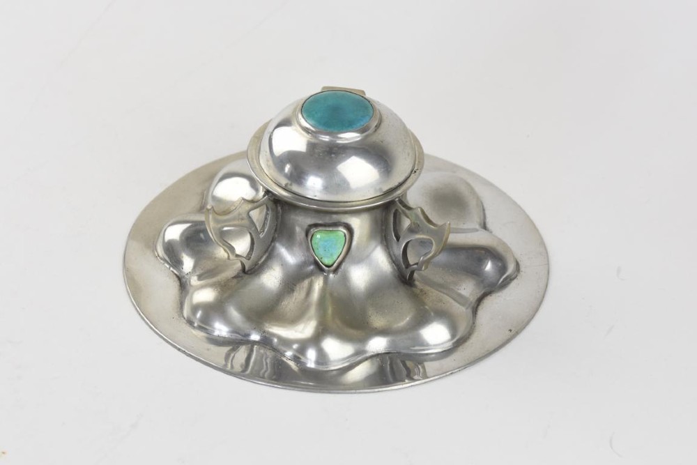 A polished pewter Arts and Crafts inkwell featuring a flared lobed base, stylized handles, and two inset turquoise ceramic cabochons.
