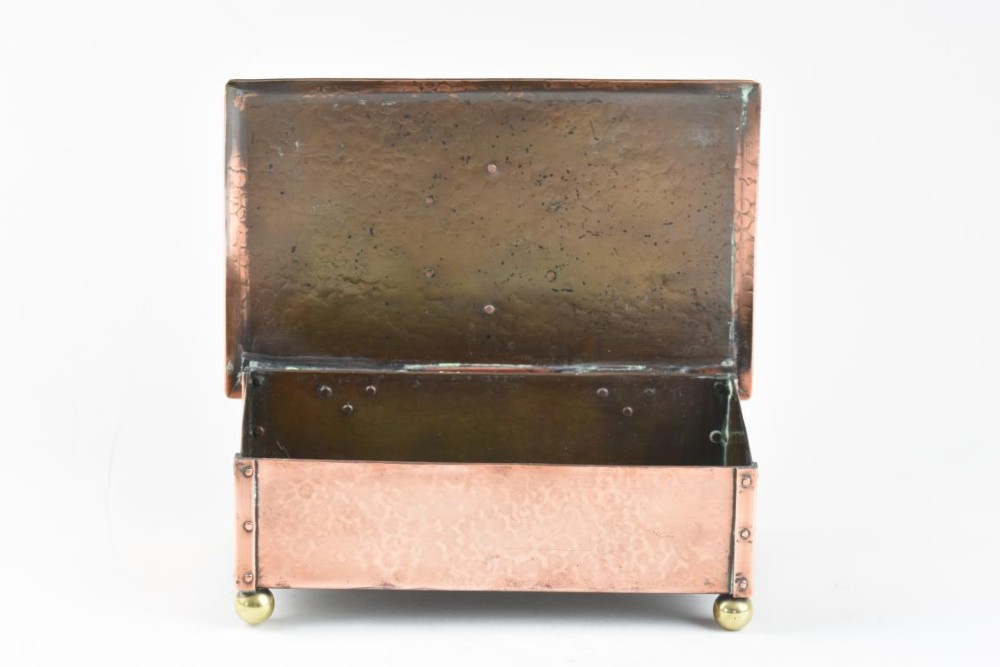 A rectangular hand-hammered copper box featuring brass ball feet, riveted corners, and a central blue enamel cabochon with a pierced butterfly overlay on the lid. View V
