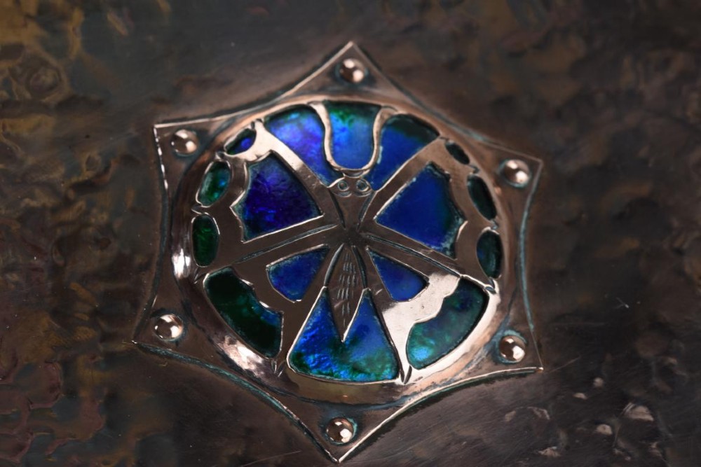 A rectangular hand-hammered copper box featuring brass ball feet, riveted corners, and a central blue enamel cabochon with a pierced butterfly overlay on the lid. View VI