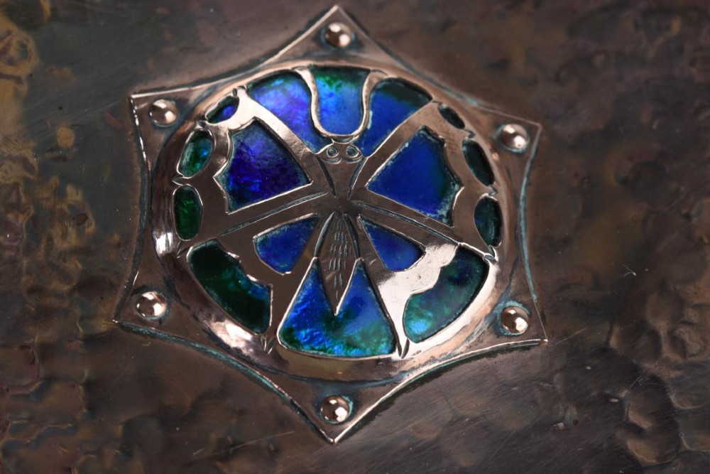 A rectangular hand-hammered copper box featuring brass ball feet, riveted corners, and a central blue enamel cabochon with a pierced butterfly overlay on the lid. View VII