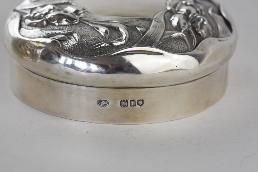 A cylindrical Art Nouveau sterling silver box with a fitted lid, decorated with raised repousse iris motifs. View VI