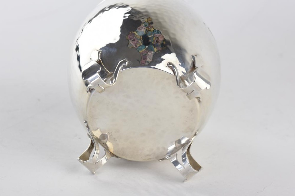 An Arts and Crafts hammered sterling silver tea caddy featuring a planished surface, looped feet, and a flat lid with a scrolled handle. View VI