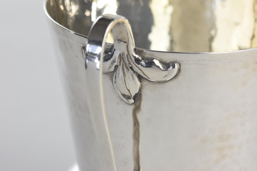 A hand-hammered silver three-handled tyg cup with a planished finish and stylized handle mounts. View V