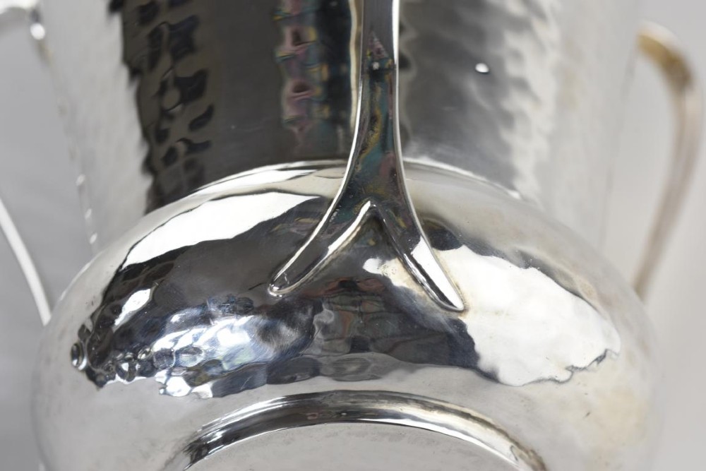 A hand-hammered silver three-handled tyg cup with a planished finish and stylized handle mounts. View VI