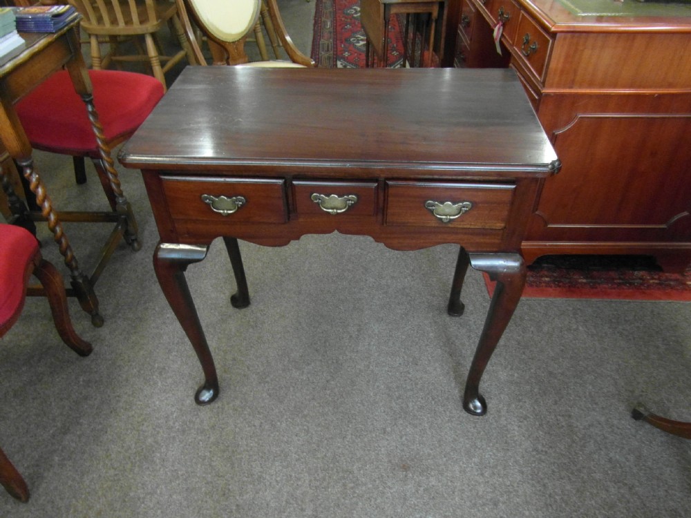 A Georgian dark mahogany lowboy featuring three drawers with brass handles, a shaped lower apron, and cabriole legs ending in pad feet.