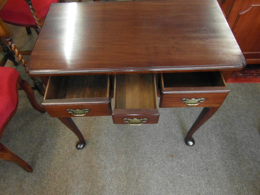 A Georgian dark mahogany lowboy featuring three drawers with brass handles, a shaped lower apron, and cabriole legs ending in pad feet. View V