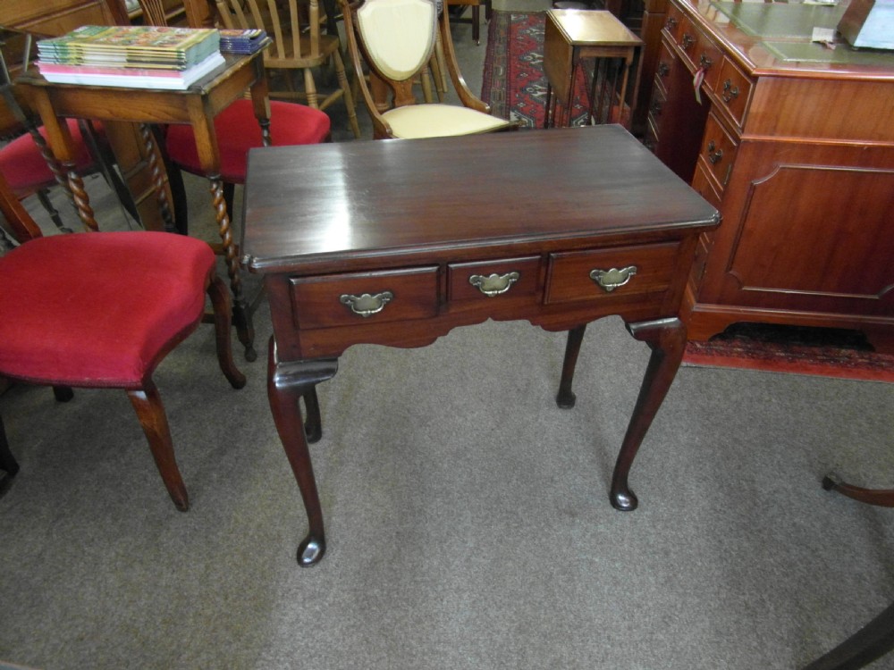 A Georgian dark mahogany lowboy featuring three drawers with brass handles, a shaped lower apron, and cabriole legs ending in pad feet. View VII