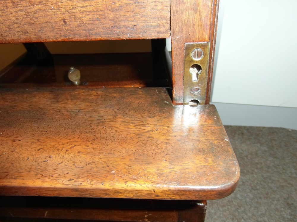 An antique Georgian mahogany childs high chair featuring a carved pierced splat back, wooden safety bar, upholstered seat, and integrated footrest on a wooden stand. View III