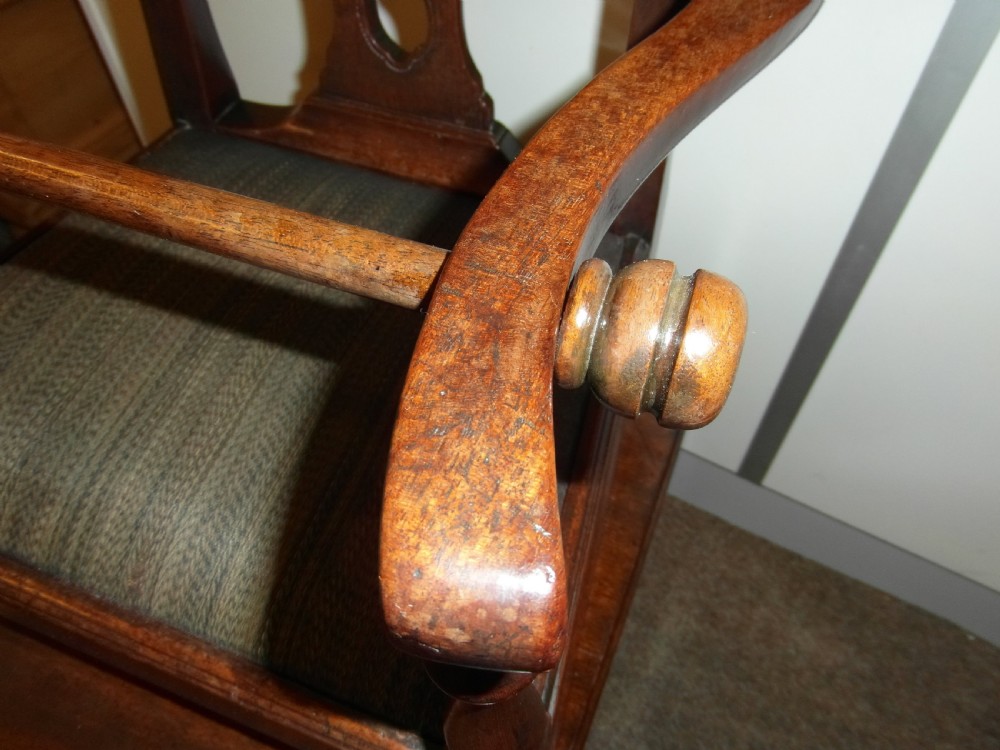 An antique Georgian mahogany childs high chair featuring a carved pierced splat back, wooden safety bar, upholstered seat, and integrated footrest on a wooden stand. View IV