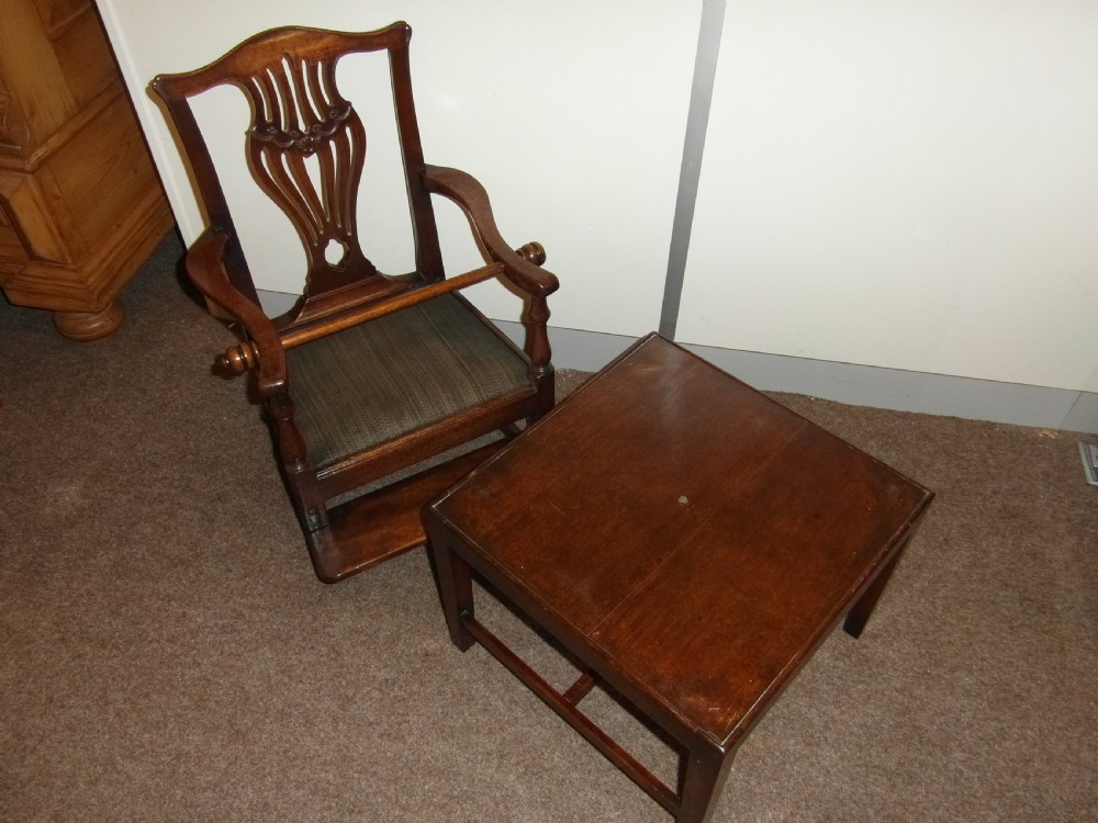 An antique Georgian mahogany childs high chair featuring a carved pierced splat back, wooden safety bar, upholstered seat, and integrated footrest on a wooden stand. View VII