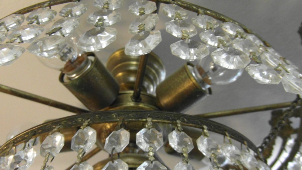A tiered Art Deco cut glass chandelier featuring strings of crystal beads suspended from an ornate dark metal gallery with decorative scrollwork. View IV