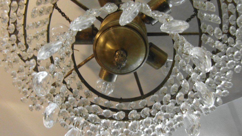 A tiered Art Deco cut glass chandelier featuring strings of crystal beads suspended from an ornate dark metal gallery with decorative scrollwork. View V