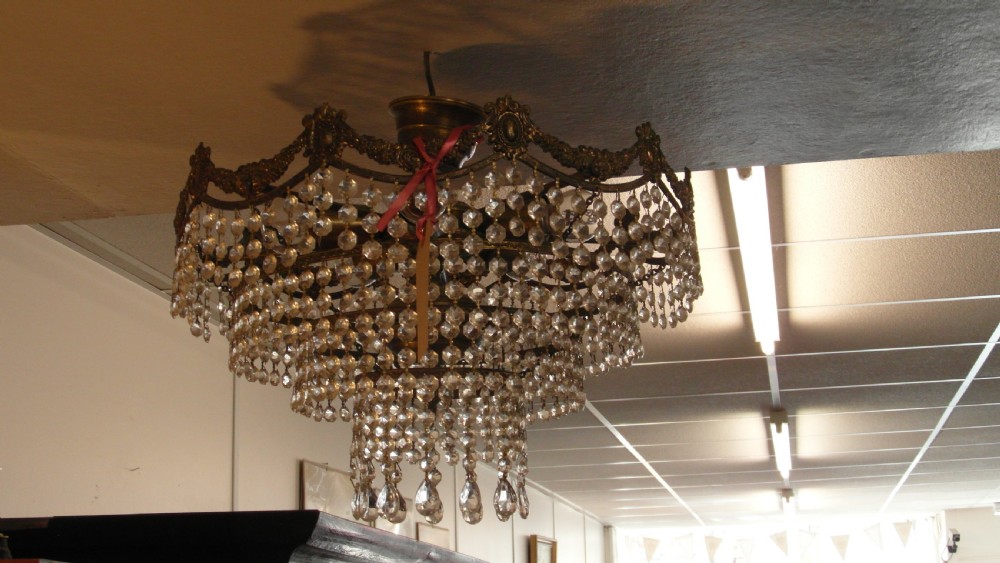 A tiered Art Deco cut glass chandelier featuring strings of crystal beads suspended from an ornate dark metal gallery with decorative scrollwork. View VI