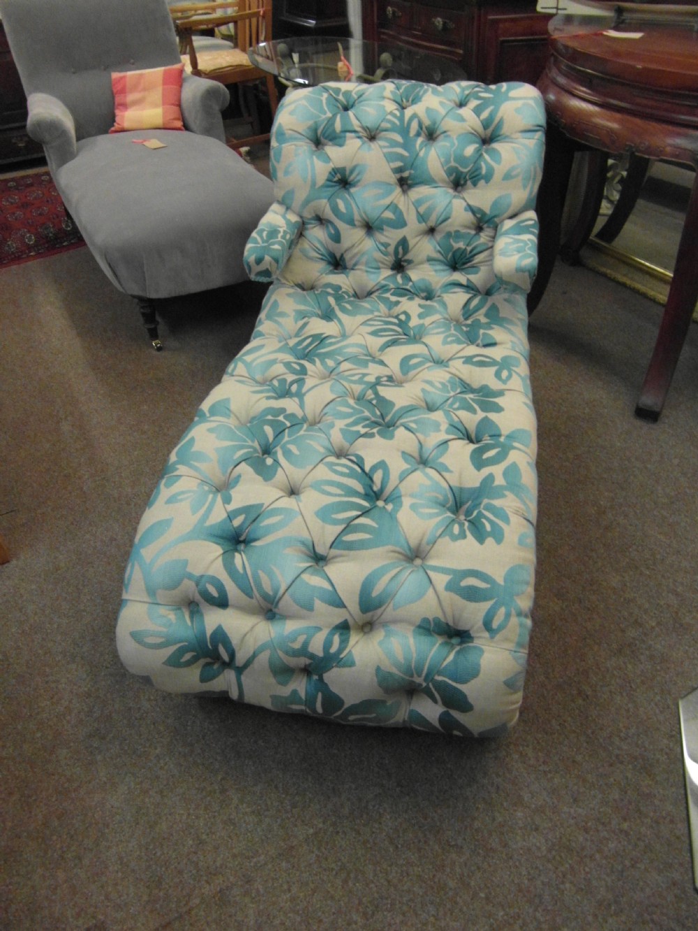 A Victorian upholstered chaise longue featuring deep-buttoned tufting in a teal and cream floral pattern with short turned wooden legs. View II