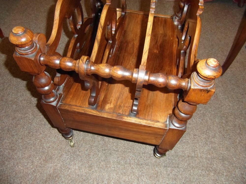 A Regency period rosewood music canterbury featuring carved scroll dividers, turned corner posts, a single base drawer with twin wooden knobs, and brass castors. View II