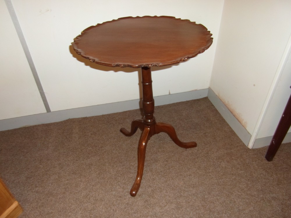 A circular dark mahogany side table featuring a carved pie-crust scalloped top supported on a turned central column and three cabriole tripod legs. View V