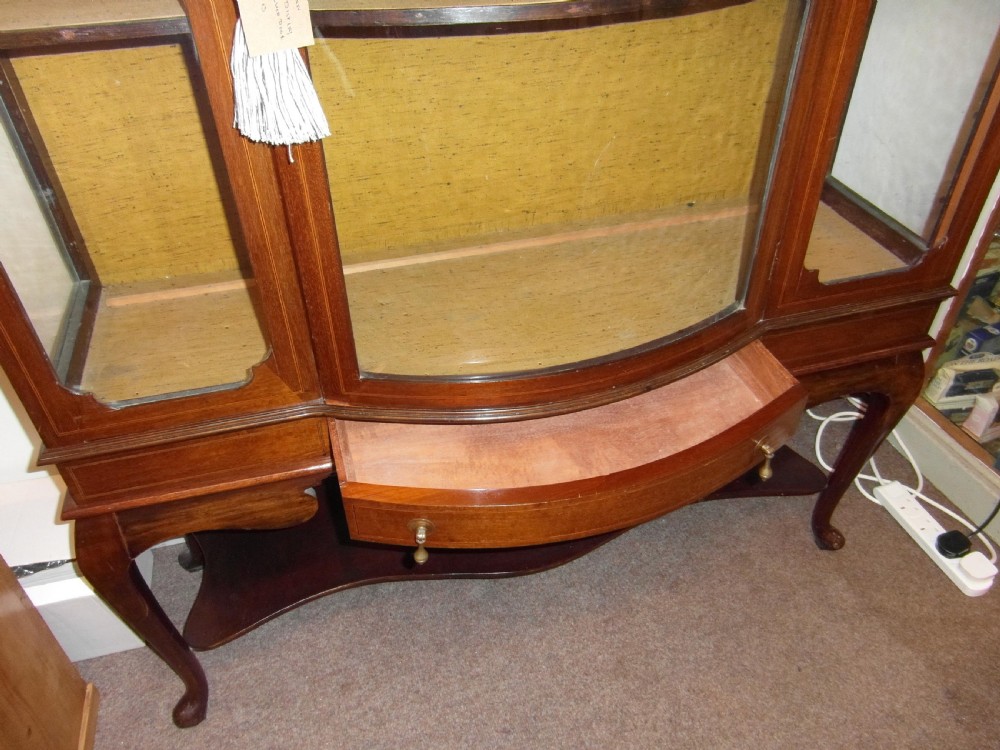 An Edwardian mahogany display cabinet featuring a bow-front glazed central section, side glass panels, interior shelves, and string inlay. View III