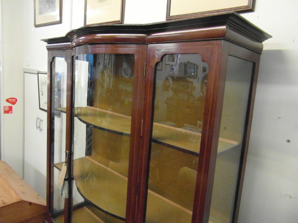 An Edwardian mahogany display cabinet featuring a bow-front glazed central section, side glass panels, interior shelves, and string inlay. View V