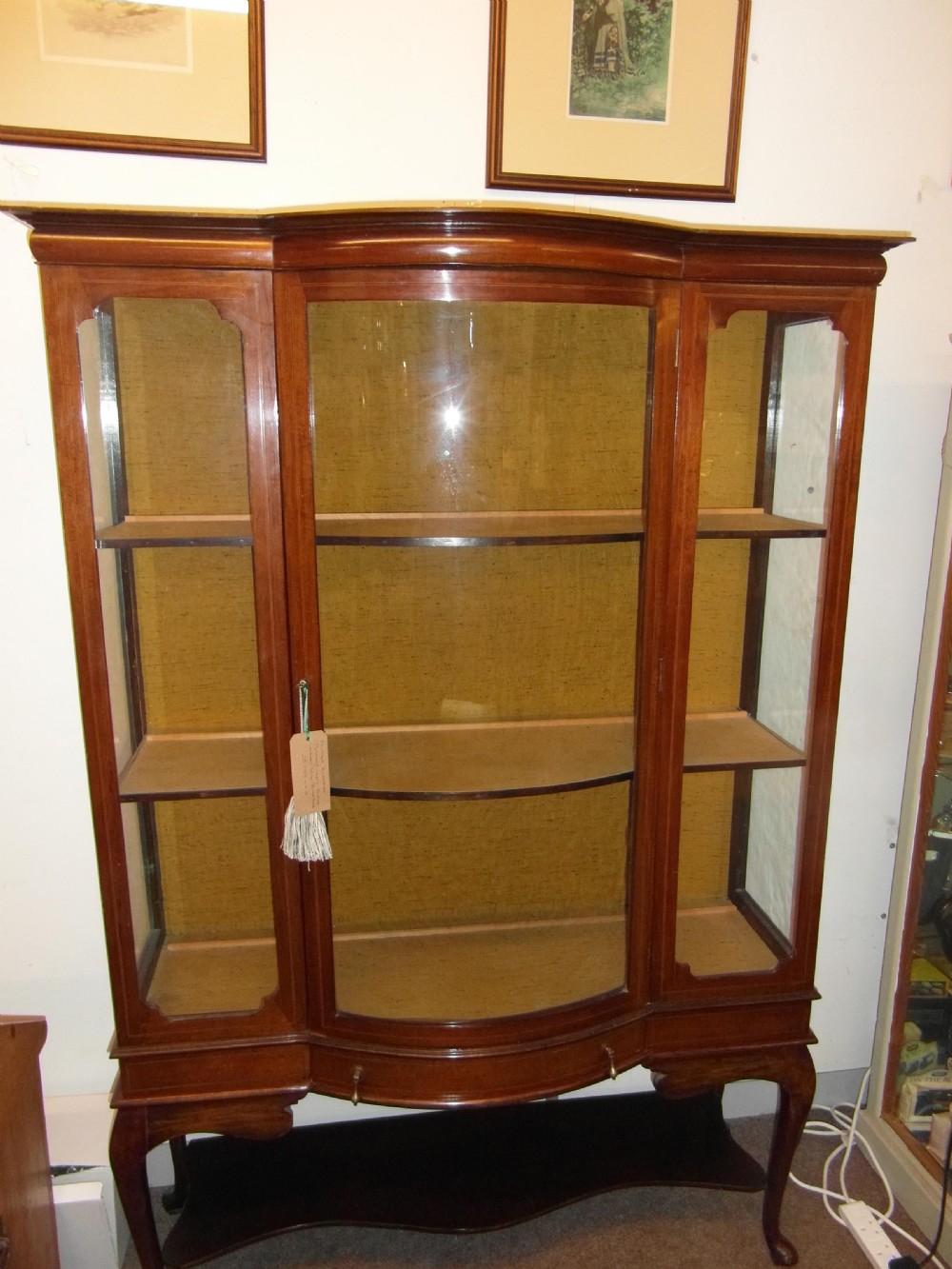 An Edwardian mahogany display cabinet featuring a bow-front glazed central section, side glass panels, interior shelves, and string inlay. View VII