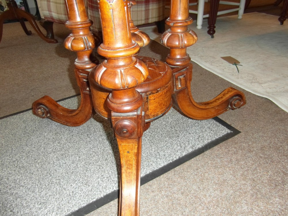A Victorian octagonal walnut centre table with turned column supports, carved scrolled legs, and porcelain castors. View III
