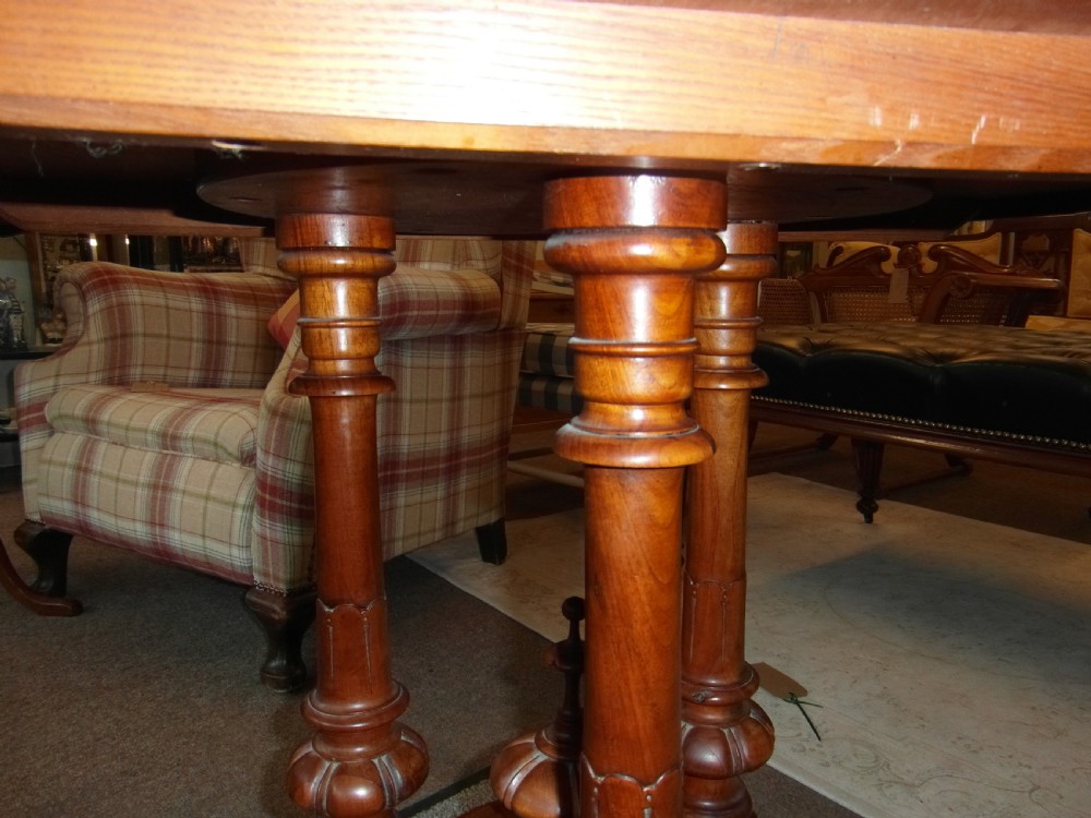 A Victorian octagonal walnut centre table with turned column supports, carved scrolled legs, and porcelain castors. View IV