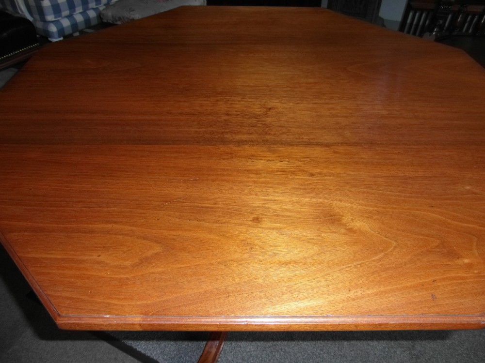 A Victorian octagonal walnut centre table with turned column supports, carved scrolled legs, and porcelain castors. View VI